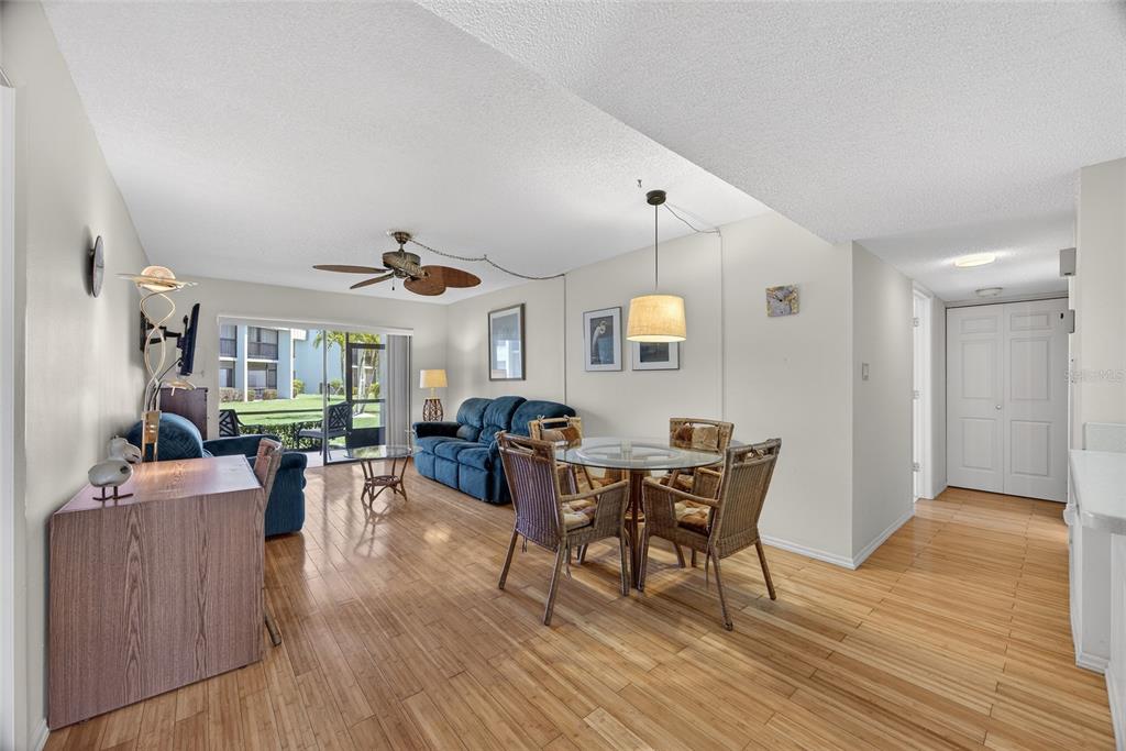 A living and dining area with hardwood floors, wicker chairs, and a glass-topped table — 1461 AQUI ESTA DRIVE UNIT B3, PUNTA GORDA, FL