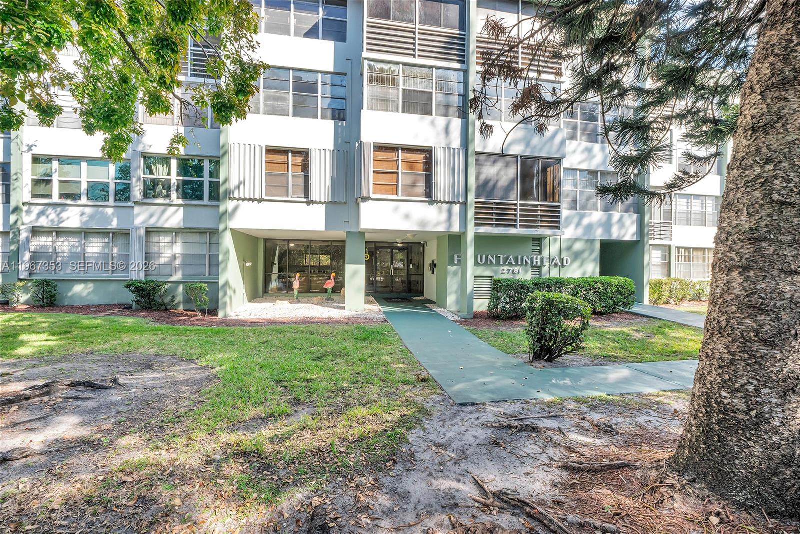 The exterior of a multi-story apartment building features a green walkway leading to the entrance — 2781 Taft St # 303, Hollywood FL 33020, HOLLYWOOD, FL