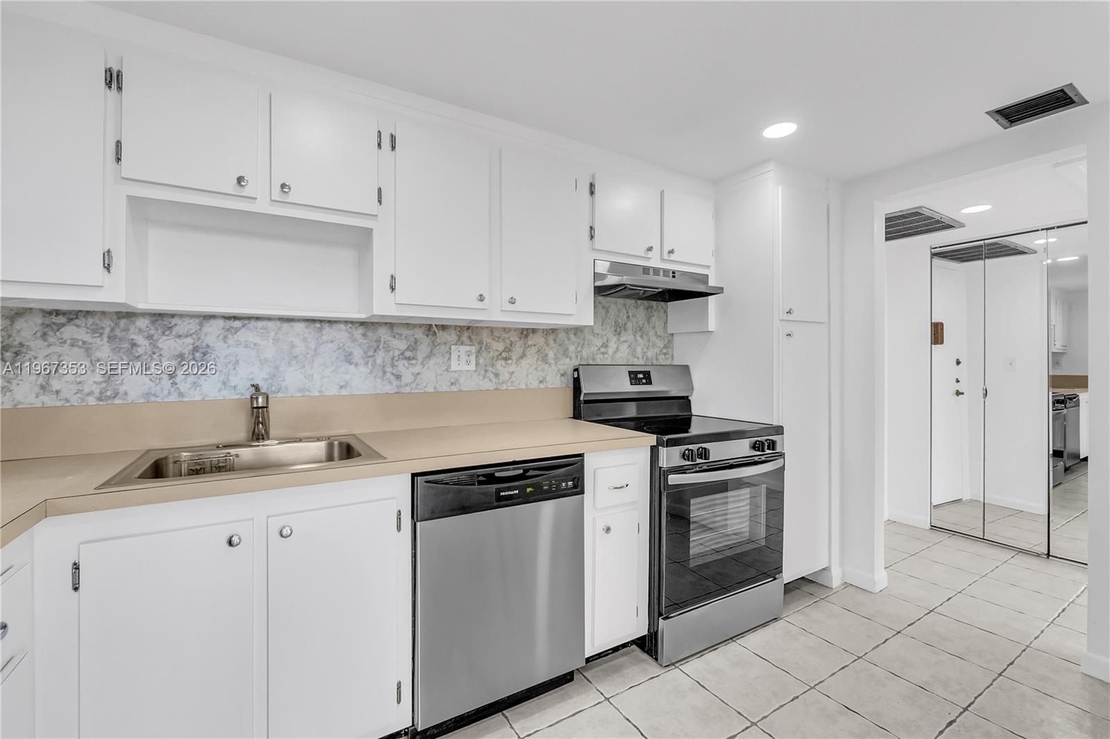 A kitchen features white cabinets, stainless steel appliances, a tan countertop, and tiled flooring — 2781 Taft St # 303, Hollywood FL 33020, HOLLYWOOD, FL