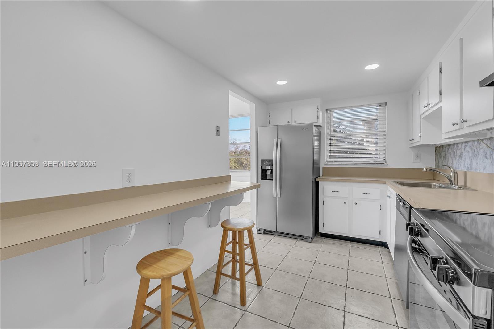 A kitchen features white cabinets, a stainless steel refrigerator, a breakfast bar, and tile flooring — 2781 Taft St # 303, Hollywood FL 33020, HOLLYWOOD, FL