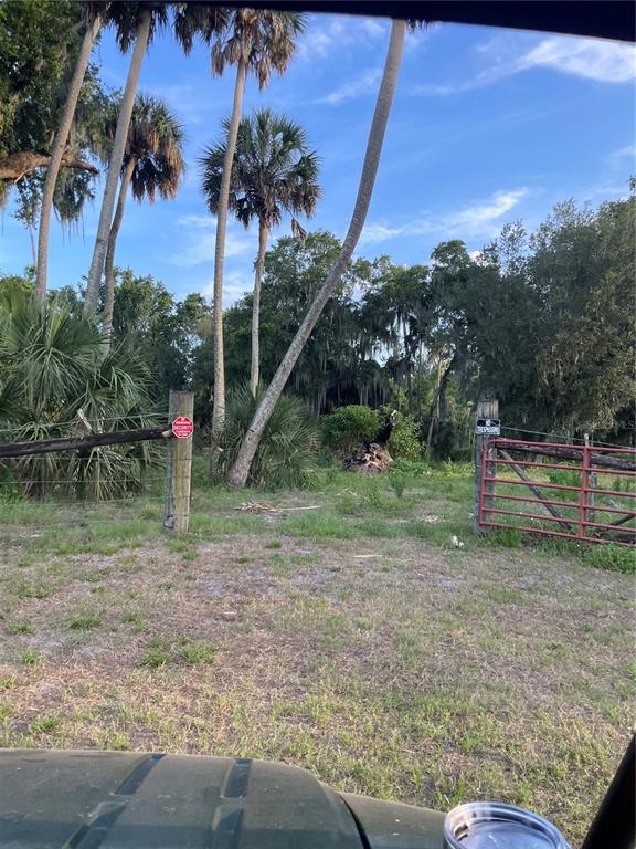 A gated entrance with a red metal fence and palm trees on a grassy lot — LAKE MARION ROAD W, HAINES CITY, FL