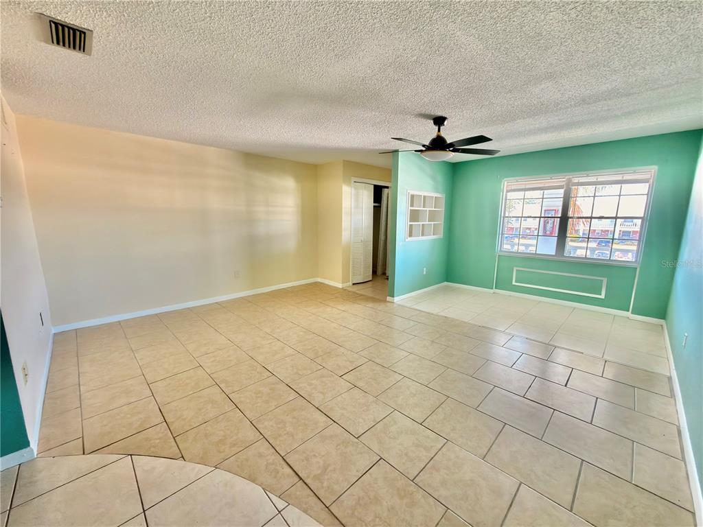 An open-concept living area features beige tile flooring, a ceiling fan, and teal accent walls — 4747 AZALEA DRIVE UNIT 229, NEW PORT RICHEY, FL