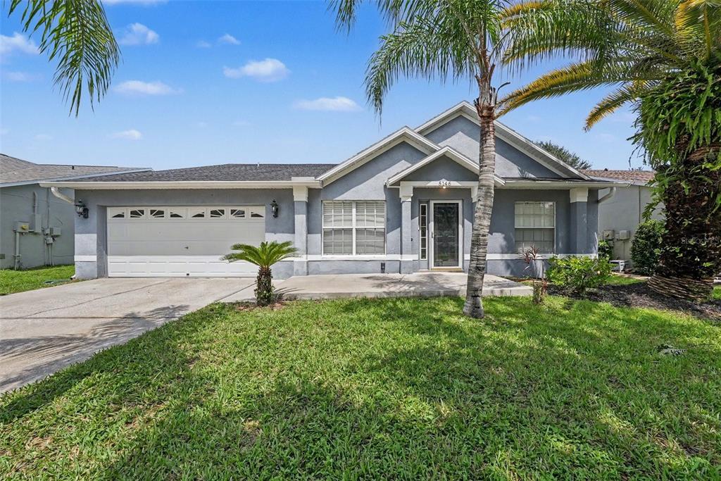 A single-story house with a gray stucco exterior, a two-car garage, and a palm tree — 5146 NEW SAVANNAH CIRCLE, WESLEY CHAPEL, FL