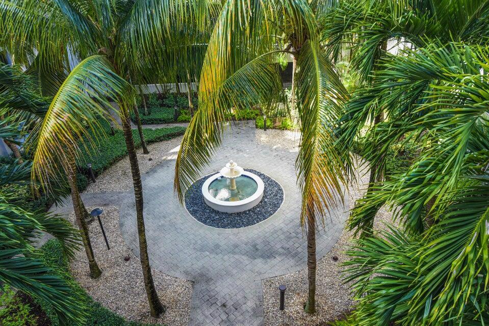 An aerial view of a circular stone patio featuring a central fountain surrounded by palm trees — 1660 Renaissance Commons Boulevard # 2407, Boynton Beach FL 33426, BOYNTON BEACH, FL