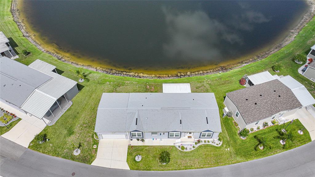 An aerial view shows a house with a gray roof situated beside a lake — 12116 SW COUNTY RD. 769 # 136, LAKE SUZY, FL