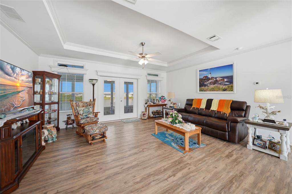 A living room with wood-look flooring, a tray ceiling, and a brown leather sofa — 12116 SW COUNTY RD. 769 # 136, LAKE SUZY, FL