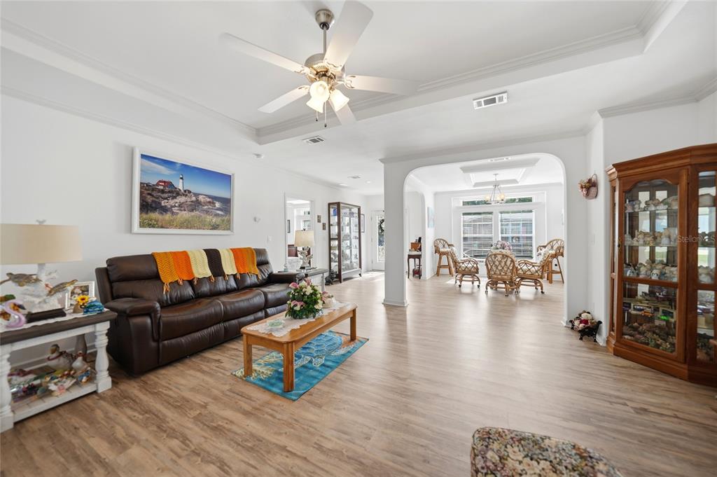 A living room with a brown leather sofa, wood flooring, and an arched entryway — 12116 SW COUNTY RD. 769 # 136, LAKE SUZY, FL