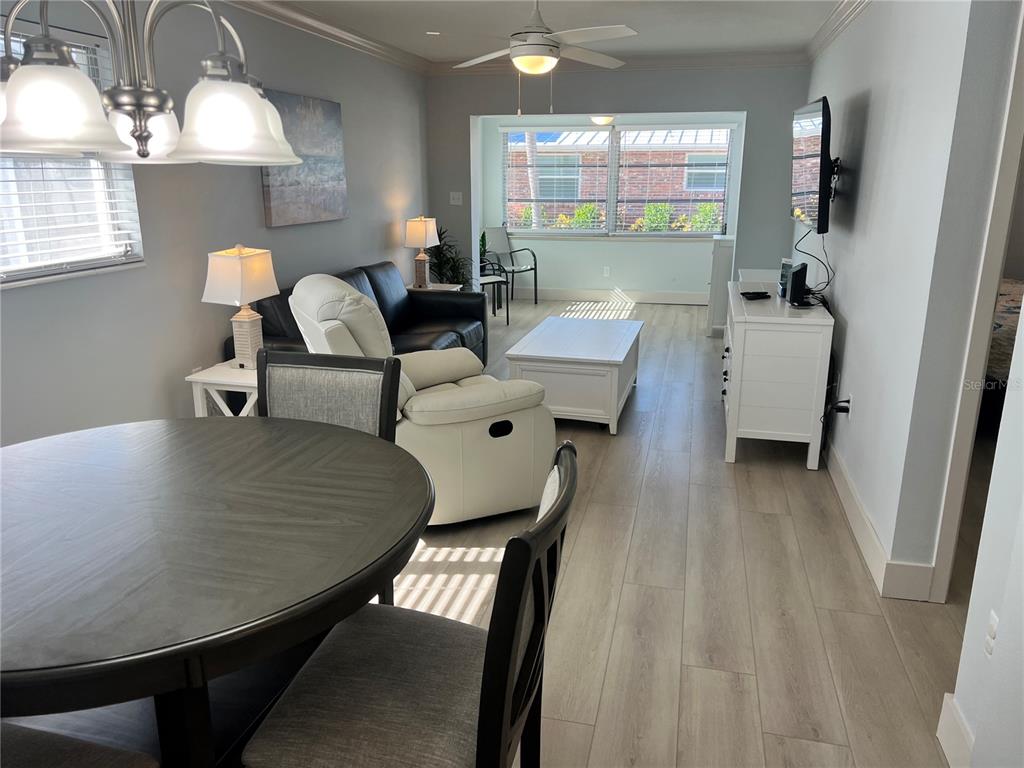A dining area opens into a living room with light wood floors and a ceiling fan — 6020 MIDNIGHT PASS ROAD UNIT 32, SARASOTA, FL