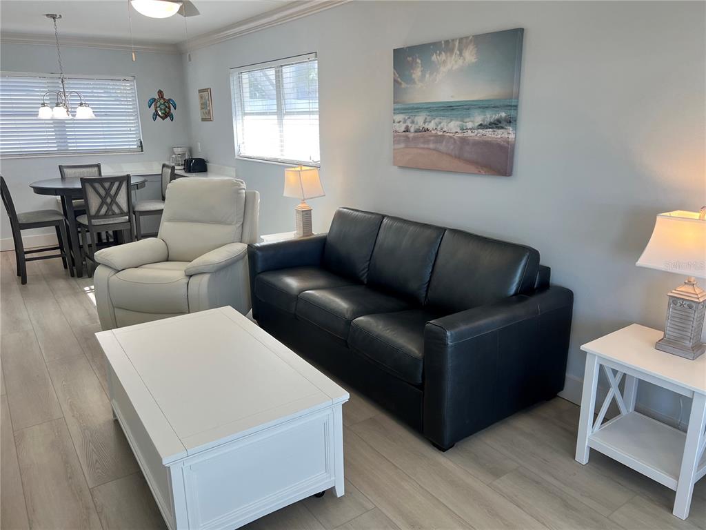 A living room features a black leather sofa, white recliner, coffee table, and dining area — 6020 MIDNIGHT PASS ROAD UNIT 32, SARASOTA, FL