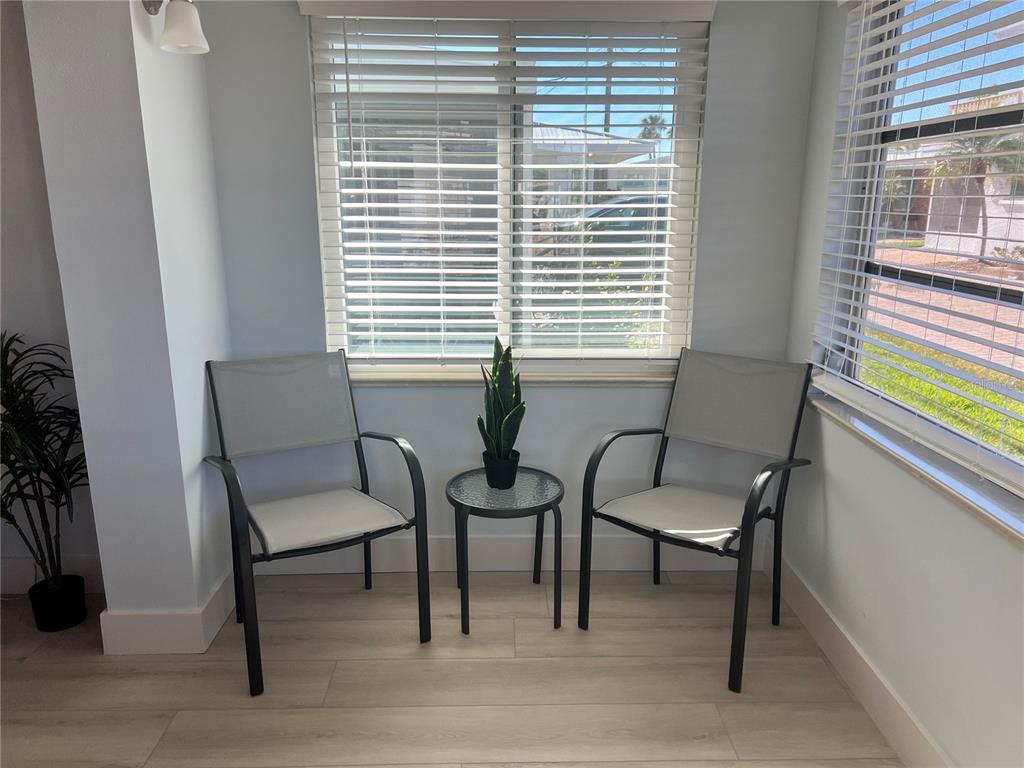 A sunroom features two chairs, a small glass table with a plant, and window blinds — 6020 MIDNIGHT PASS ROAD UNIT 32, SARASOTA, FL