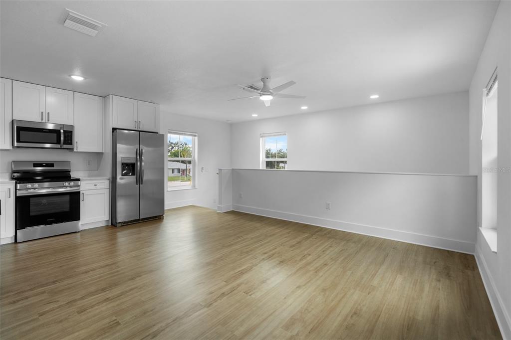 A kitchen with white cabinets and stainless steel appliances opens to a living area — 505 43RD STREET S UNIT 505 1/2, ST PETERSBURG, FL
