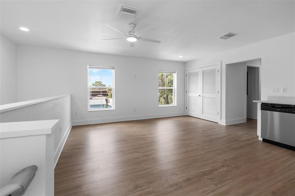 A bright, open-concept room with wood-look flooring, a ceiling fan, and white louvered doors — 505 43RD STREET S UNIT 505 1/2, ST PETERSBURG, FL