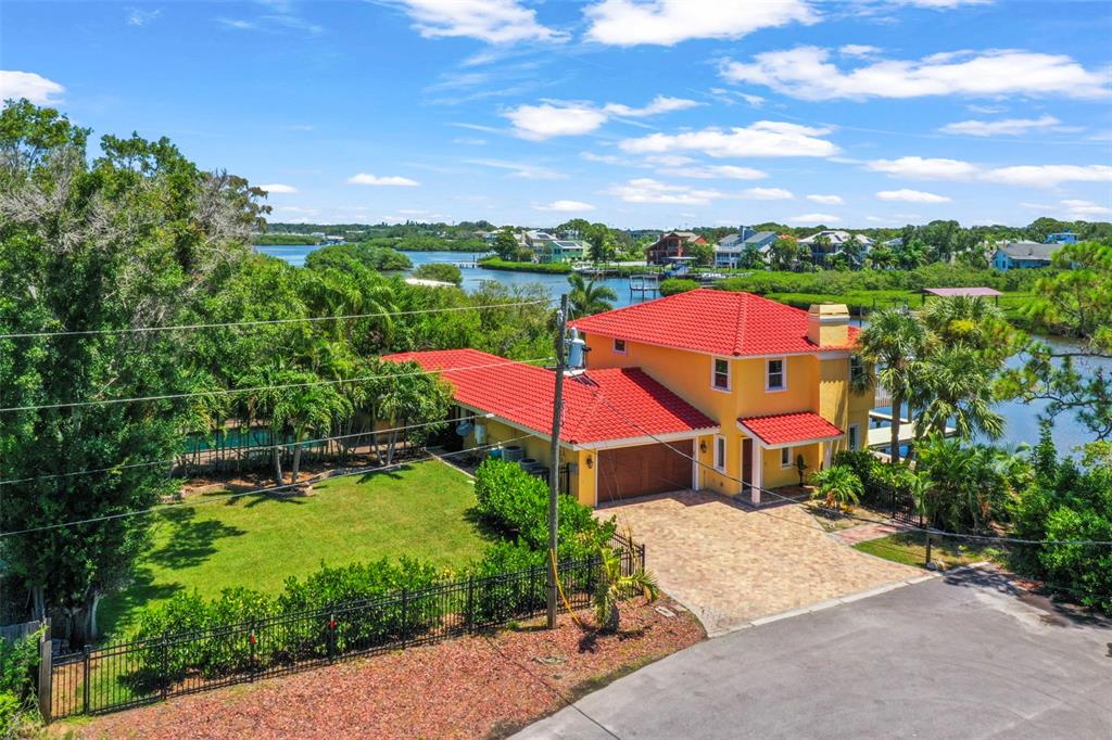 An aerial view of a yellow two-story house with a red tile roof and driveway — 412 ORCHID LANE, PALM HARBOR, FL