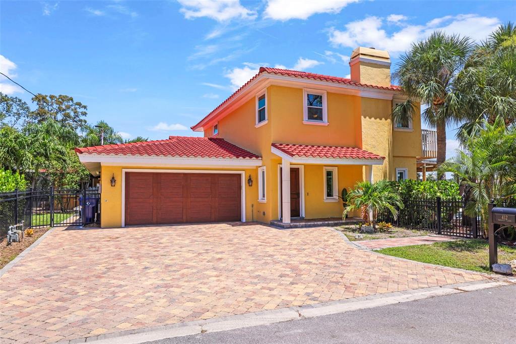 A two-story yellow house with a red tile roof and a paved driveway — 412 ORCHID LANE, PALM HARBOR, FL