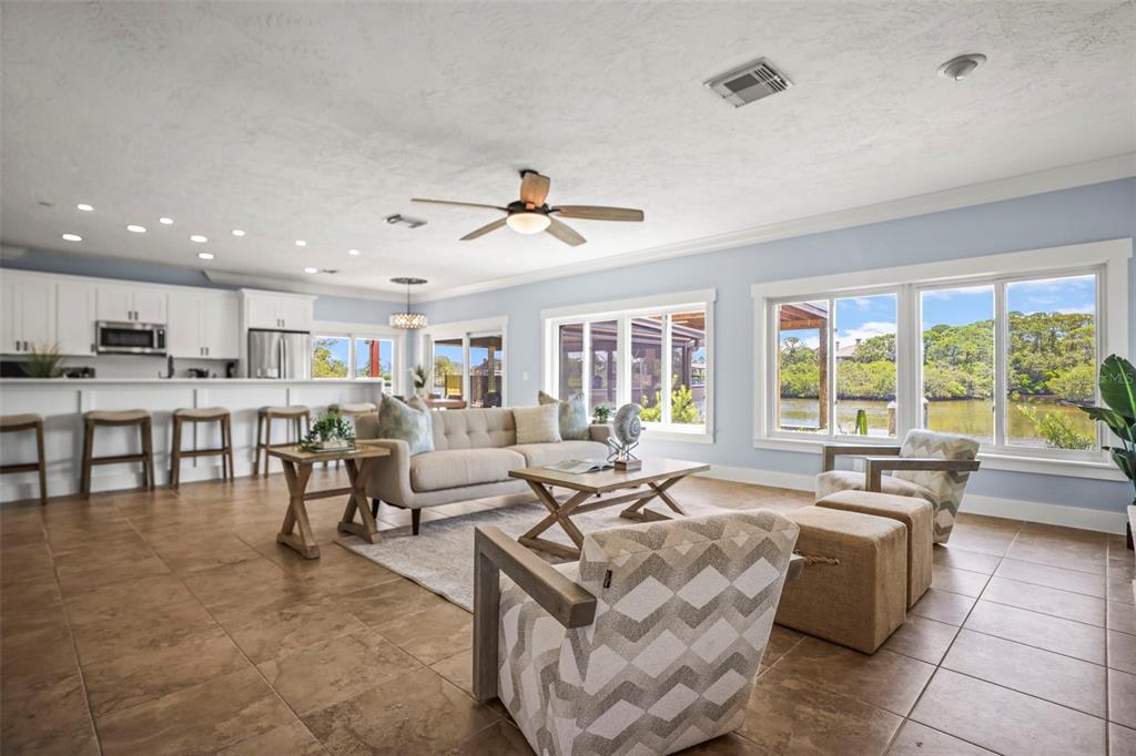 An open-concept living room and kitchen with tile floors, a ceiling fan, and water views — 412 ORCHID LANE, PALM HARBOR, FL