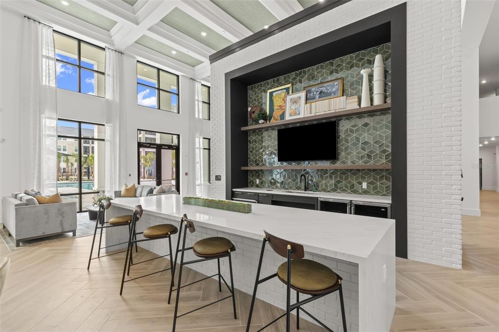 A modern lounge features a large kitchen island, bar seating, and a tiled media wall — 7210 INTERBAY BOULEVARD UNIT C1, TAMPA, FL