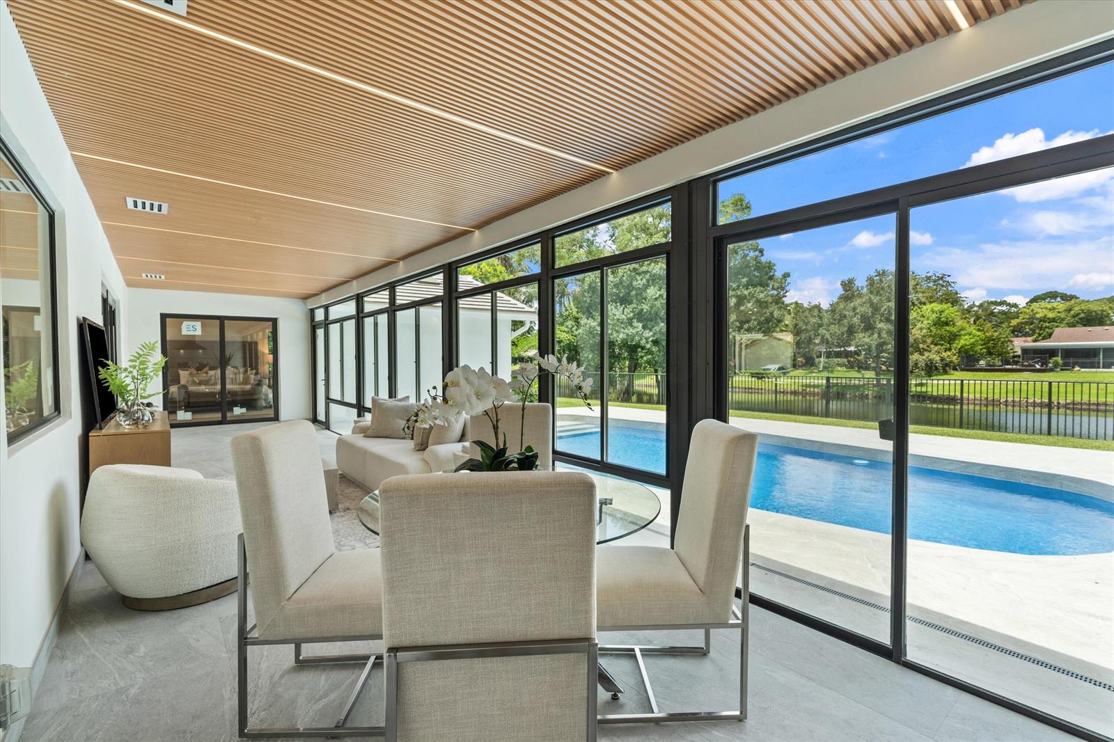 A sunroom with a slatted wood ceiling, tile floors, and sliding glass doors overlooking a pool — 2413 NW 26th Street, Boca Raton FL 33431, BOCA RATON, FL