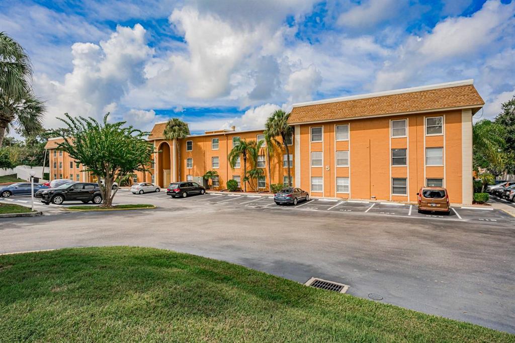 A three-story orange apartment building with a parking lot and palm trees in front — 12760 INDIAN ROCKS ROAD UNIT 555, LARGO, FL