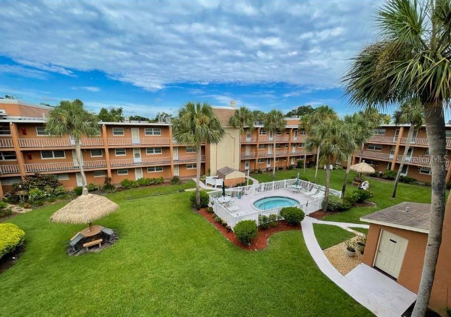 An elevated view of a multi-story apartment complex courtyard featuring a pool and palm trees — 12760 INDIAN ROCKS ROAD UNIT 555, LARGO, FL