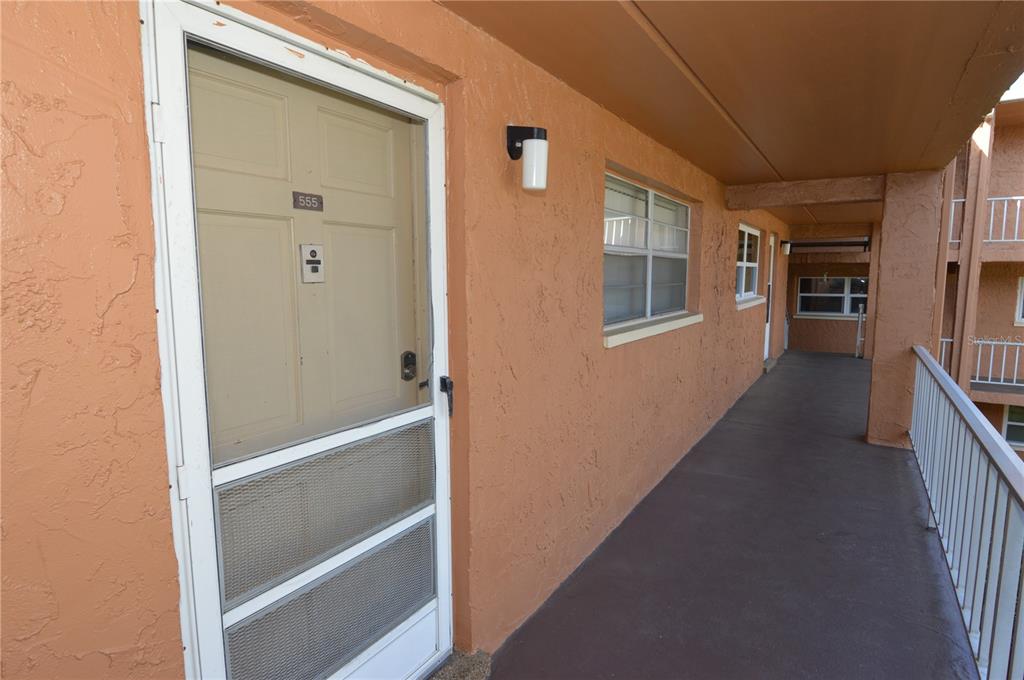An exterior view of an apartment unit entrance with a screen door and stucco walls — 12760 INDIAN ROCKS ROAD UNIT 555, LARGO, FL