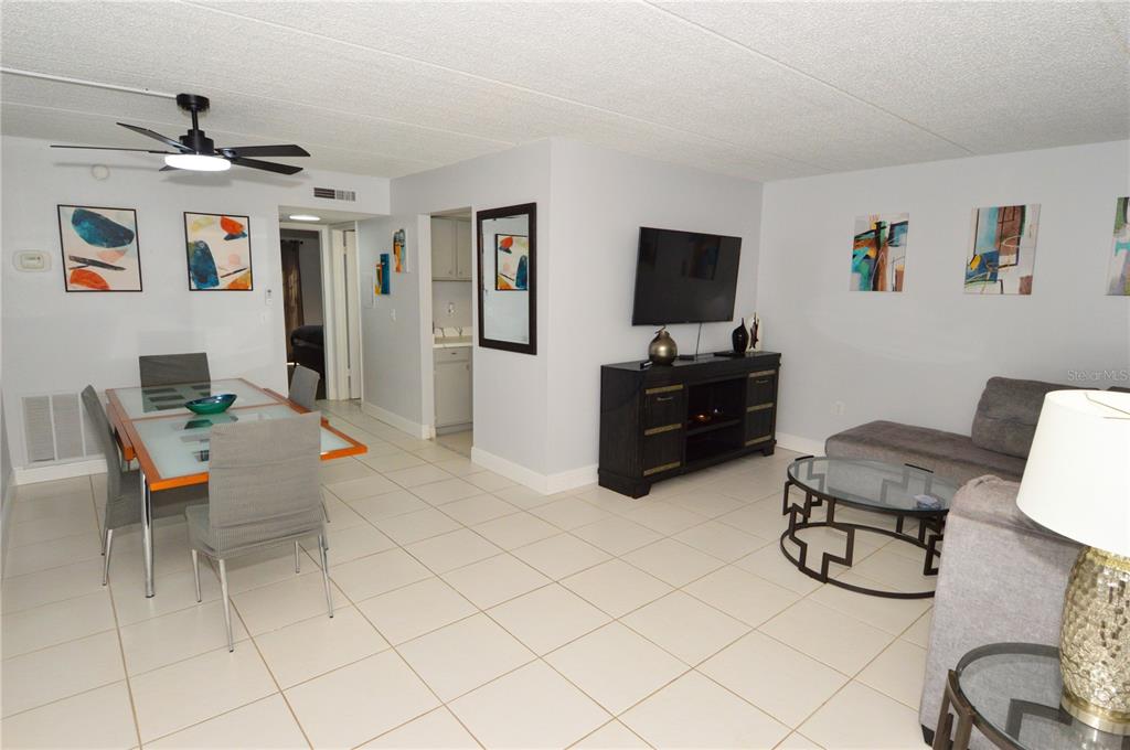 An open-concept living and dining area features tile flooring, a ceiling fan, and modern furniture — 12760 INDIAN ROCKS ROAD UNIT 555, LARGO, FL