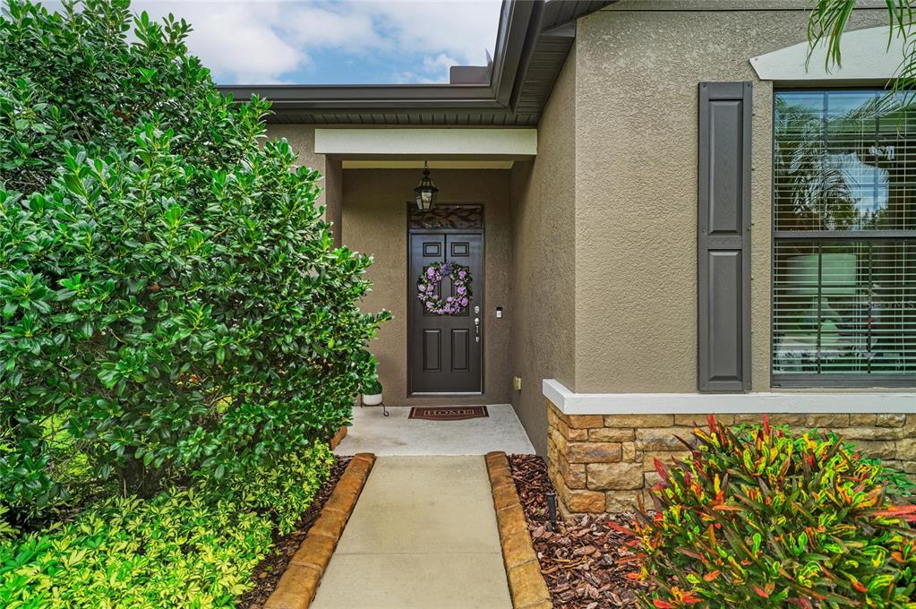 A concrete walkway leads to the front entrance of a house with a dark door — 5508 105TH TERRACE E, PARRISH, FL
