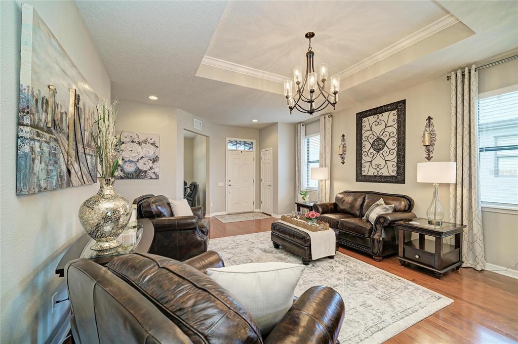 A living room features dark leather furniture, a tray ceiling, and a chandelier — 5508 105TH TERRACE E, PARRISH, FL