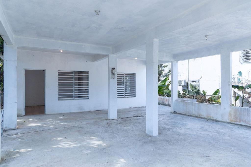 A covered concrete patio area features white walls, support columns, and two windows with shutters — 378 CALLE GIRASOLES, VIEQUES, PR
