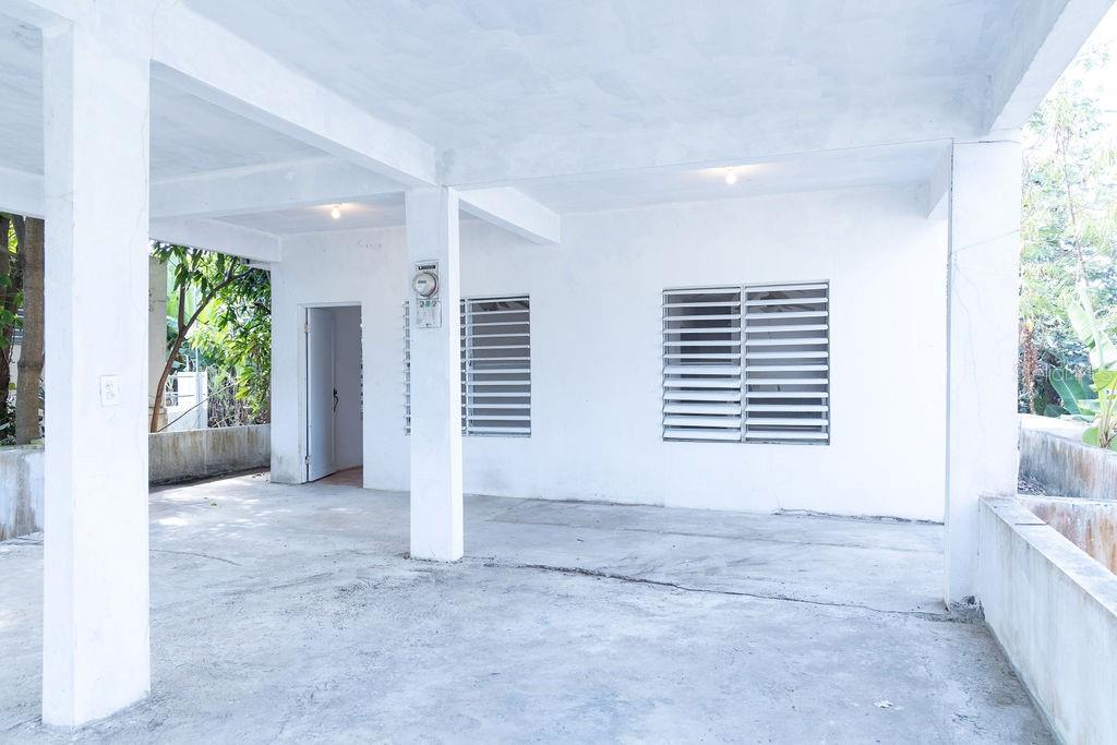 A covered concrete patio area features white walls, two louvered windows, and a doorway — 378 CALLE GIRASOLES, VIEQUES, PR