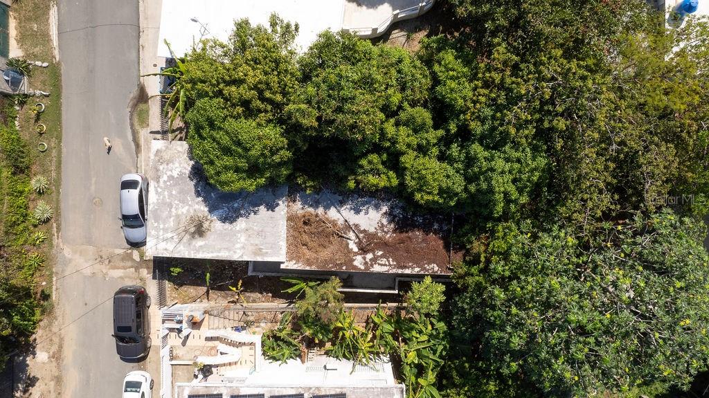 An aerial view shows a house with a flat roof and surrounding trees near a street — 378 CALLE GIRASOLES, VIEQUES, PR