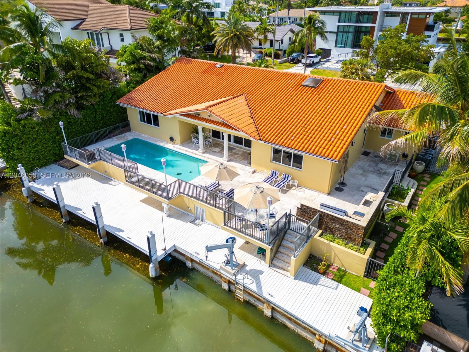 An aerial view shows a waterfront house with an orange tile roof, pool, and dock — 1115 San Pedro Ave, Coral Gables FL 33156, CORAL GABLES, FL