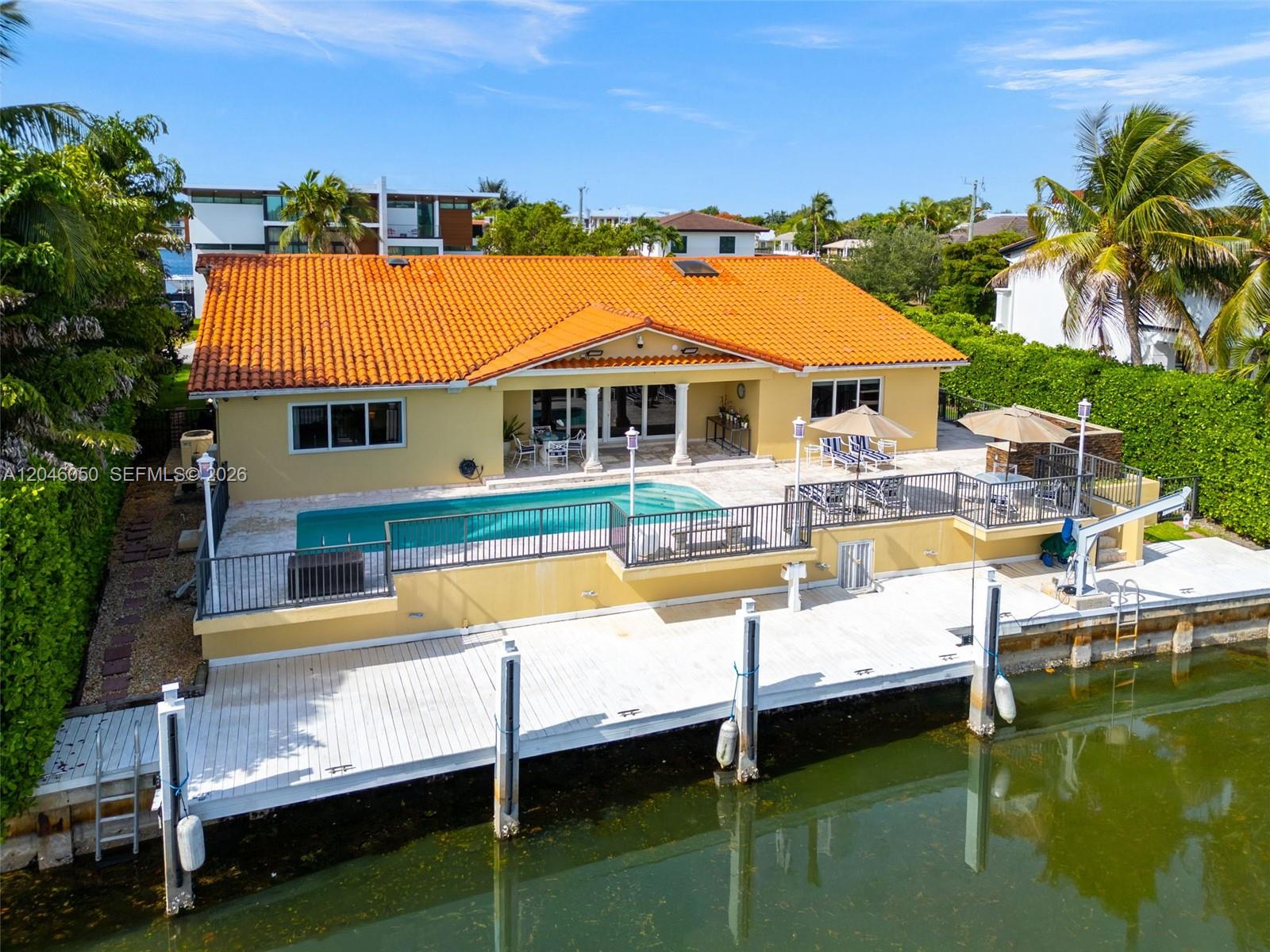 An aerial view shows a yellow house with an orange tile roof, pool, and dock — 1115 San Pedro Ave, Coral Gables FL 33156, CORAL GABLES, FL