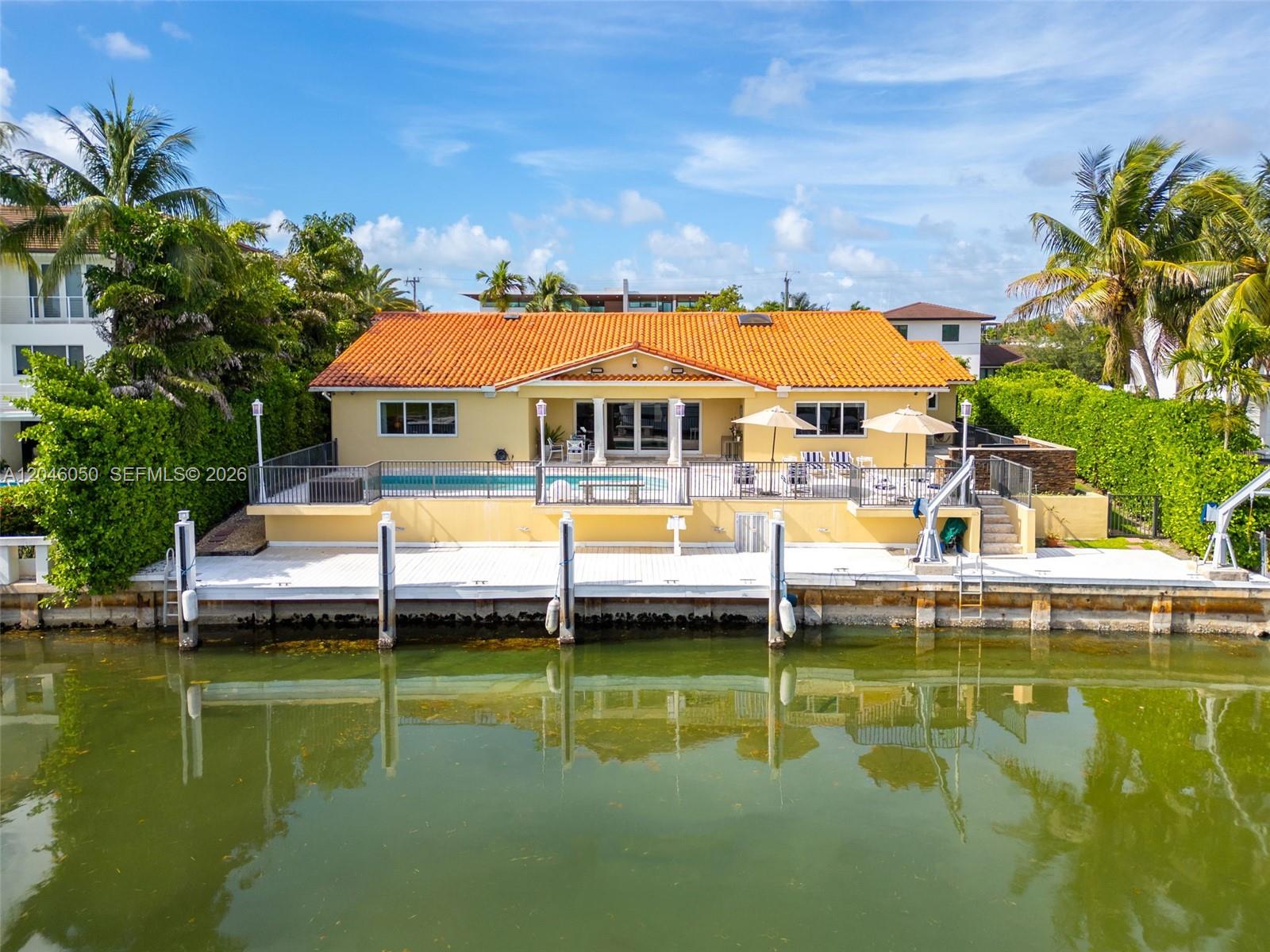 A yellow house with a terracotta roof features a waterfront pool deck and boat dock — 1115 San Pedro Ave, Coral Gables FL 33156, CORAL GABLES, FL
