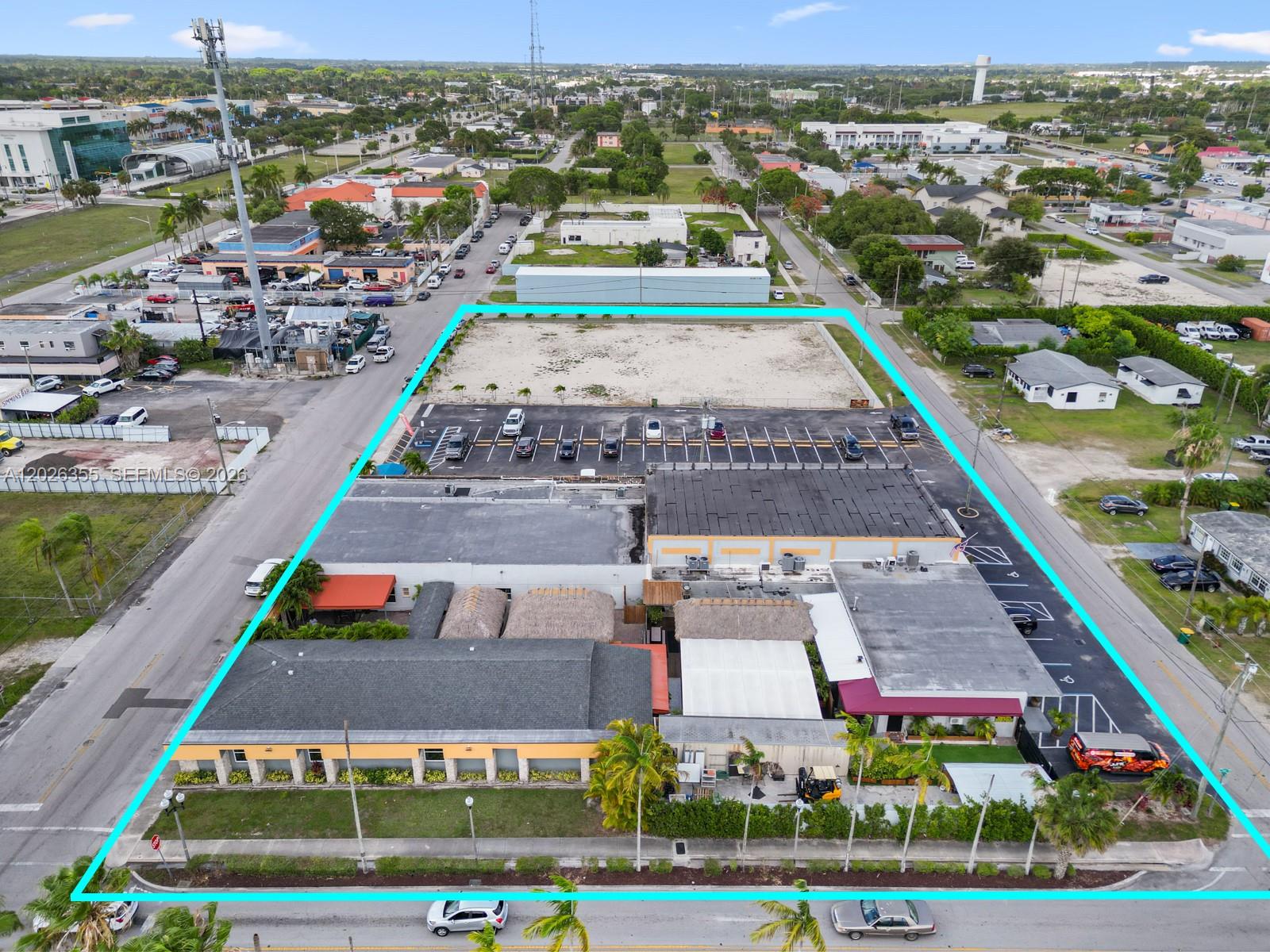 An aerial view shows a commercial property with a large parking lot and vacant land — 17 NE 1st Rd, Homestead FL 33030, HOMESTEAD, FL