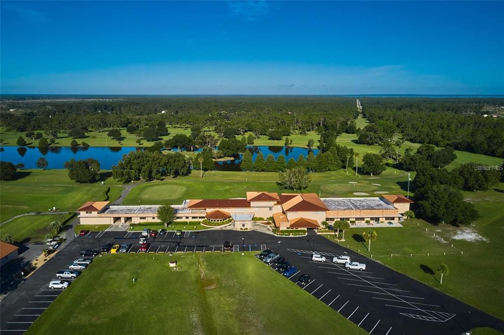 An aerial view shows a large clubhouse building with a parking lot and golf course — 419 BELMONTE DRIVE, INDIAN LAKE ESTATES, FL