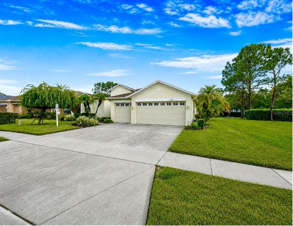 A single-story house with a beige exterior, a three-car garage, and a concrete driveway — 10924 RAIN HOLLOW COURT, NEW PORT RICHEY, FL