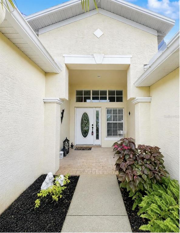 A paved walkway leads to the front entrance of a house with a white door — 10924 RAIN HOLLOW COURT, NEW PORT RICHEY, FL