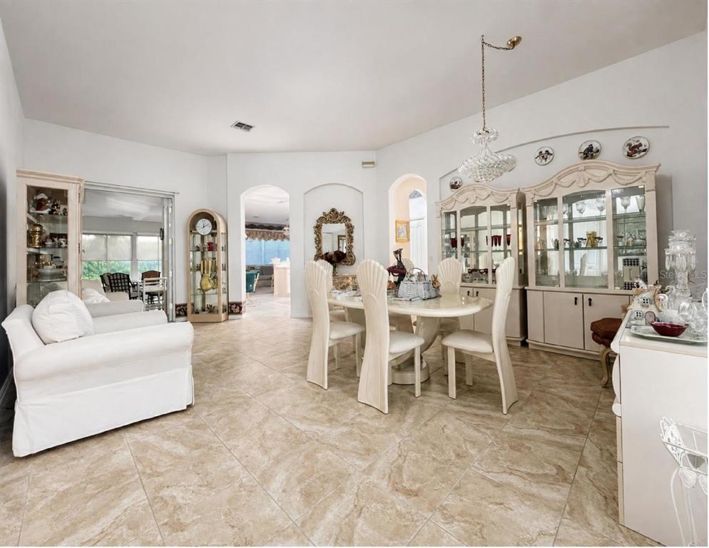 A dining room with a white table, chairs, and two large china cabinets on tile floors — 10924 RAIN HOLLOW COURT, NEW PORT RICHEY, FL