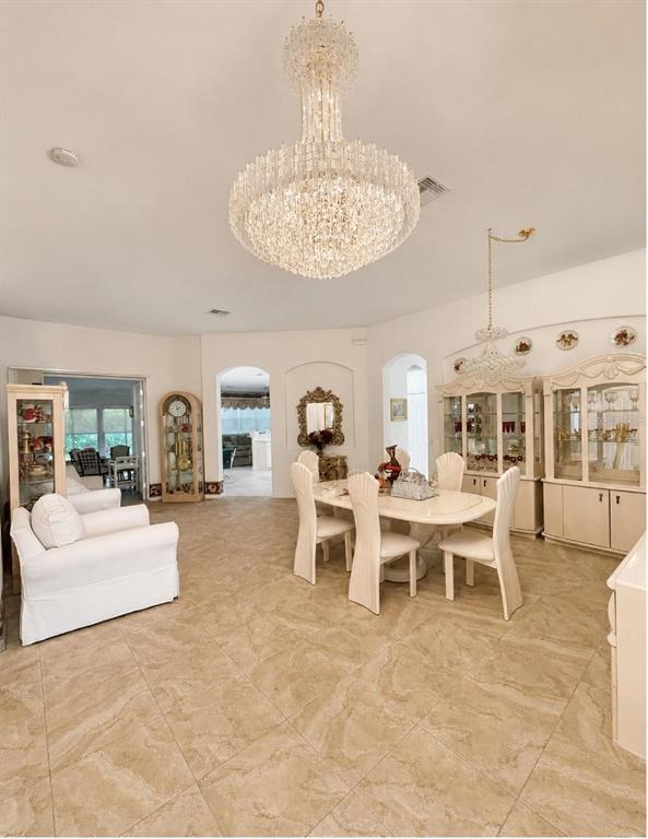 A dining room features a large crystal chandelier, tile flooring, and white furniture — 10924 RAIN HOLLOW COURT, NEW PORT RICHEY, FL