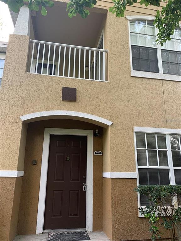 A two-story tan stucco building features a dark brown front door and a second-floor balcony — 4308 S KIRKMAN ROAD UNIT 1713, ORLANDO, FL