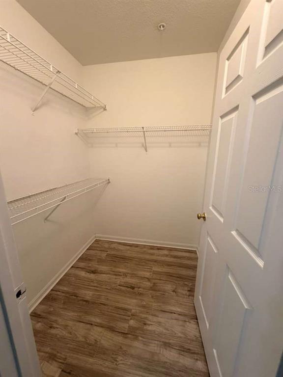 A walk-in closet features white wire shelving, light wood-look flooring, and a white door — 4308 S KIRKMAN ROAD UNIT 1713, ORLANDO, FL