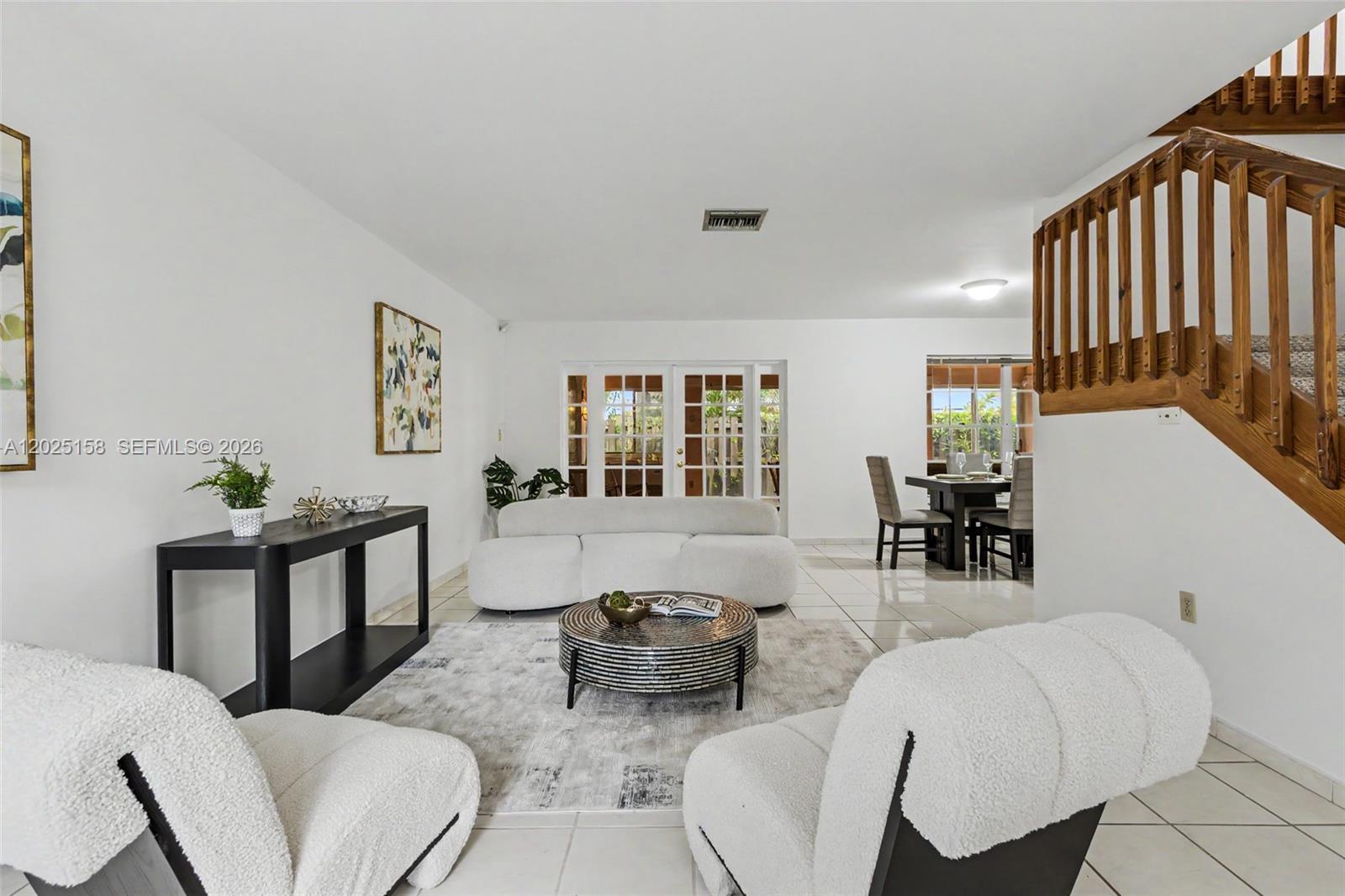 A living room with white furniture, a round coffee table, and a wooden staircase — 15033 SW 110th Ter, Miami FL 33196, MIAMI, FL