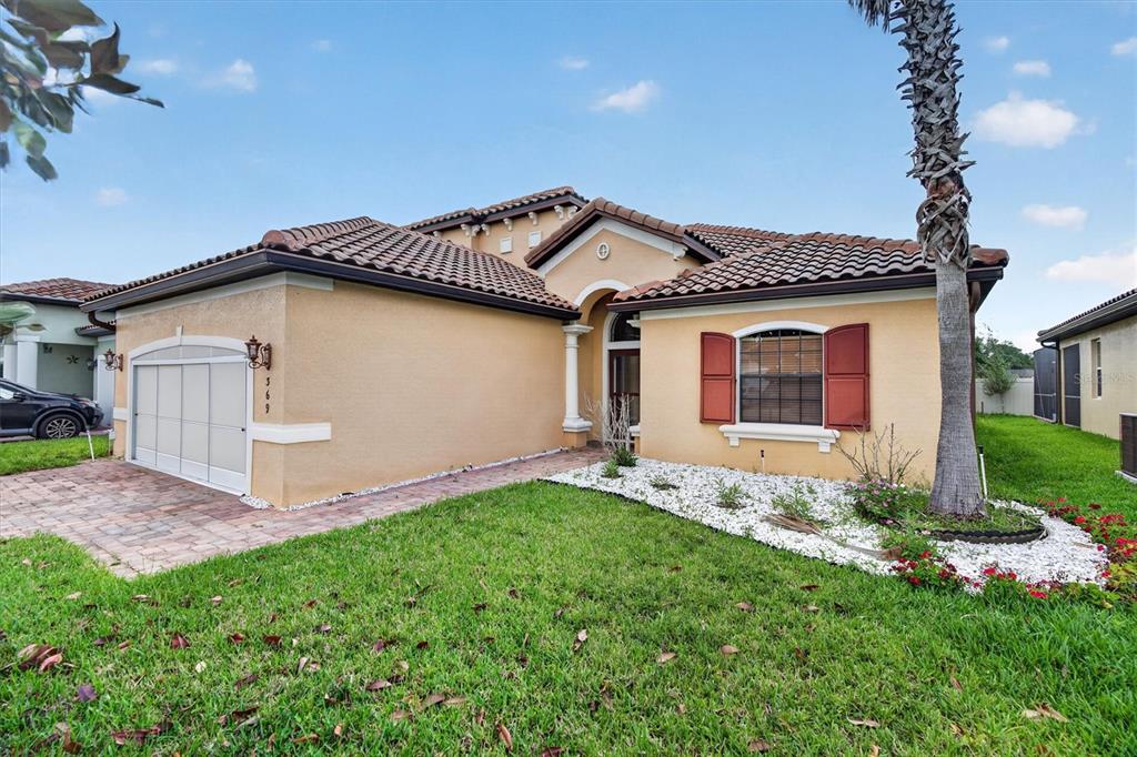 A single-story stucco house with a tile roof, garage, and red shutters — 369 VILLA SORRENTO CIRCLE, HAINES CITY, FL