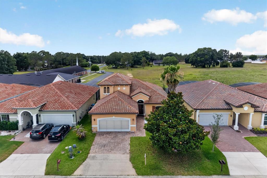 An aerial view shows a tan stucco house with a tiled roof and a paved driveway — 369 VILLA SORRENTO CIRCLE, HAINES CITY, FL