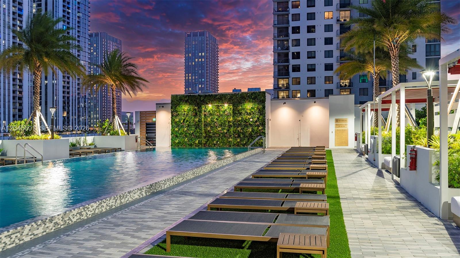 A rooftop swimming pool area features lounge chairs on artificial turf and a green wall — 650 NE 2nd Ave # 1811, Miami FL 33132, MIAMI, FL