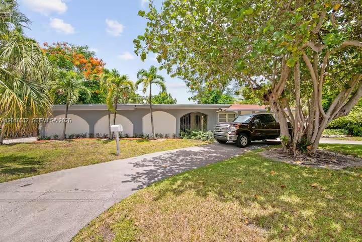 A single-story house with arched architectural details and a driveway featuring a parked truck — 13325 SW 84th Ave, Pinecrest FL 33156, PINECREST, FL