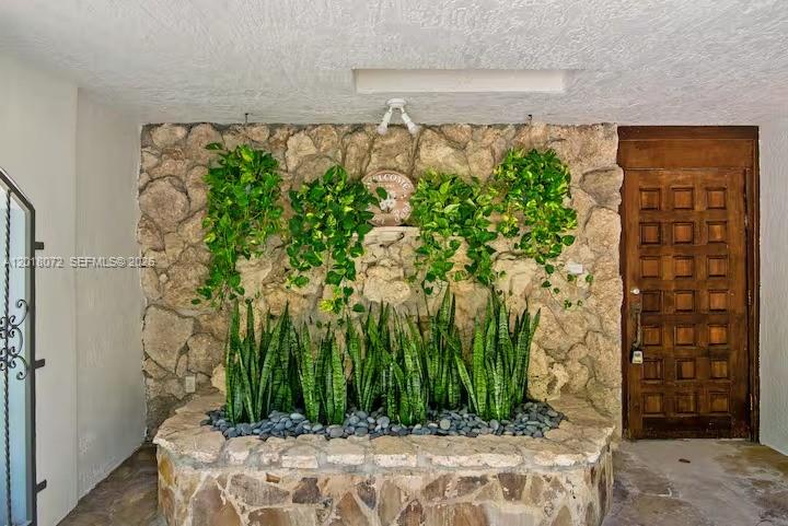 A stone planter with snake plants and hanging vines sits against a stone wall — 13325 SW 84th Ave, Pinecrest FL 33156, PINECREST, FL