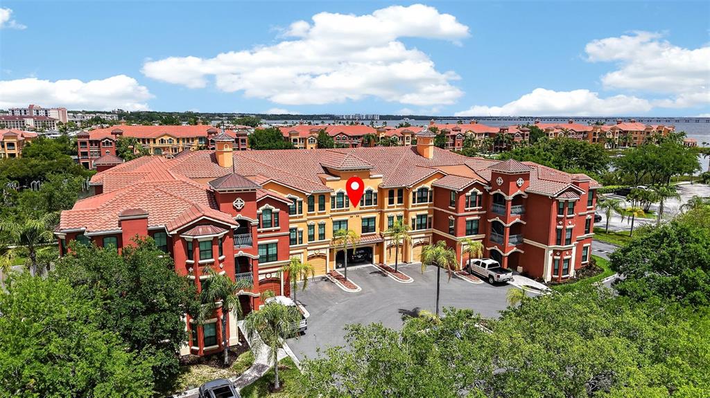An aerial view of a multi-story, Mediterranean-style apartment complex with red tile roofs — 2746 VIA TIVOLI UNIT 116A, CLEARWATER, FL