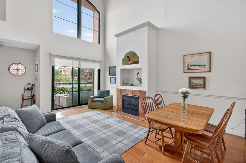 A living and dining area features a fireplace, high ceilings, and a view of water — 2746 VIA TIVOLI UNIT 116A, CLEARWATER, FL