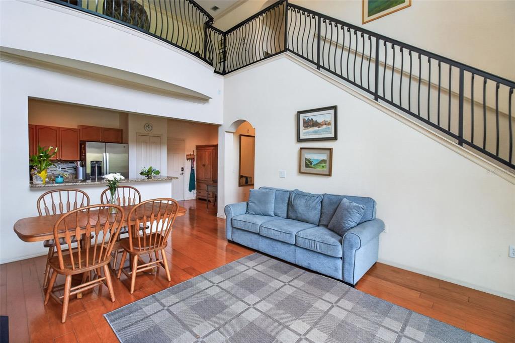 A living and dining area with hardwood floors, a blue sofa, and a staircase — 2746 VIA TIVOLI UNIT 116A, CLEARWATER, FL